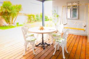 eine Veranda mit einem weißen Tisch und Stühlen auf einer Terrasse in der Unterkunft Villa neuve tout confort SHABBY CHIC in Talmont