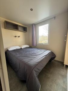 a bedroom with a large bed with a window at Au coeur de la pinède in Camiers