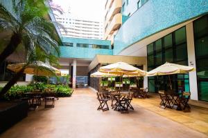an outdoor patio with tables and chairs and umbrellas at OZPED Flats Particulares Edifício Brasília Lets Ideia in Brasilia
