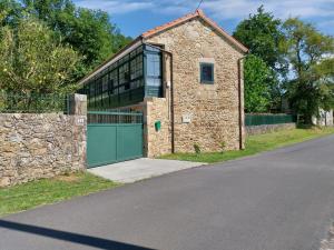 an old stone building with a green garage door at Casa Galipendre in A Estrada