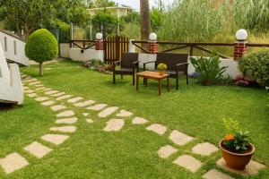 a garden with chairs and a table on the grass at Nicolas Beach in Palaiochora