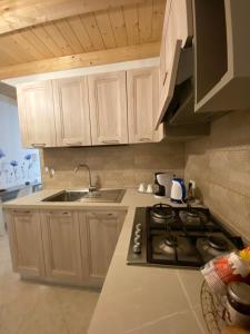 a kitchen with white cabinets and a stove top oven at Piccola Dimora Arco Ricci in LʼAquila +9 photos