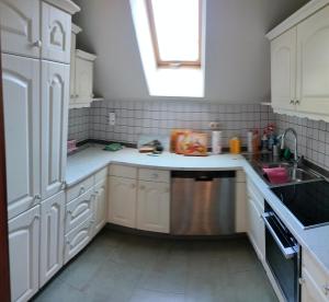 a kitchen with white cabinets and a sink and a window at Pension Kaden in Dresden