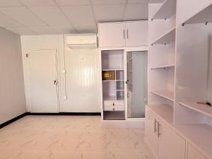 an empty kitchen with white cabinets and a refrigerator at Dhan Valley Guest House in Bhaun +10 photos