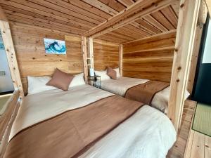 two beds in a room with wooden walls at New Open Japanese style with large bath in Ukaji