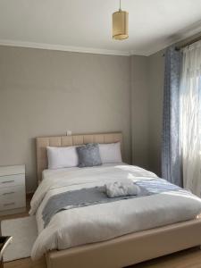 a white bedroom with a large bed and a window at Shikaz Homes Two bedroom in Nairobi