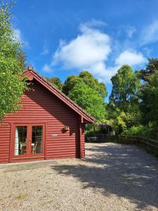 a red barn with a driveway in front of it at Springburncabins in Elgin