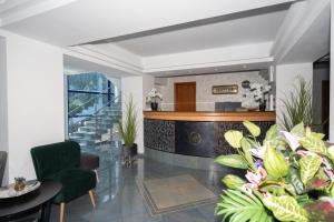 a lobby with a staircase and green chairs and plants at Excelsior Hotel Timisoara in Timişoara