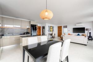 Una cocina y sala de estar con una mesa negra y sillas blancas. en Reve Samui Luxe Seafront Residence with Panoramic Views, en Ban Bang Po