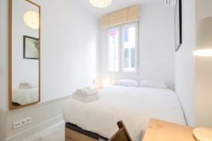 biała sypialnia z łóżkiem i lustrem w obiekcie Valverde Apartment w Madrycie