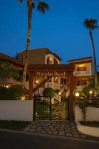 a hotel with a gate and palm trees at night at Nicolas Beach in Palaiochora