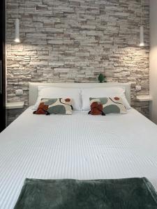 a white bed with pillows and a brick wall at Nura's - Joia city center in Alghero