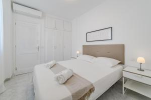 a white bedroom with a large bed and a desk at La Punta in Alcalá