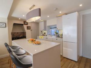 een keuken met een wit kookeiland met daarop een fruitschaal bij Rosebank Cottage in Woolacombe
