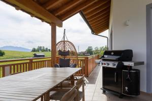 a deck with a table and a grill and a table and chairs at Idyllische Ferienunterkunft in Aidling am Riegsee in Riegsee