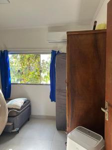 a small room with a refrigerator and a window at Casa Charme - Pé na Areia in Iguape
