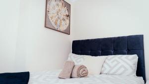 a bed with a blue headboard and two towels at Modern, comfy 2 bedroom House in Hatfield, town centre, free parking, large garden in Hatfield +14 photos