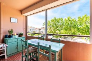 a dining room with a table and a large window at Studio Les Régates avec loggia et parking gratuit Plage du Grazel Gruissan in Gruissan