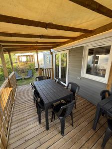 un patio avec une table et des chaises sur une terrasse dans l'établissement MOBILHOME 6-8 PERSONNES Camping LES VIVIERS 4 ETOILES CAP FERRET, à Lège-Cap-Ferret