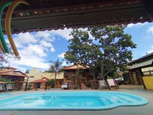 a swimming pool at a resort with a tree at Pousada Matuto Cipó in Serra do Cipo