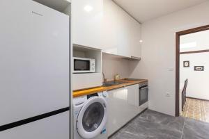 a kitchen with a washing machine and a microwave at Beach House 1 in Labruge