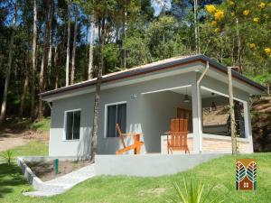 a small house with two chairs in a yard at Chales Vinhas da Harmonia l Pousada em Cunha SP in Cunha