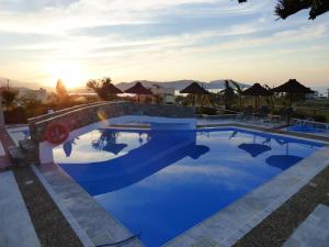 a pool at a resort with the sun setting at Poledas Apartments in Georgioupolis
