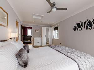 a bedroom with a large white bed with a ceiling fan at 1 bed in South Molton 83128 in Chittlehampton