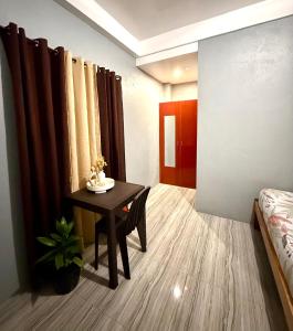 a room with a table and a bed and curtains at Shanti's Inn in General Luna