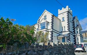 a large white building with a stone wall at Talarfor Barmouth in Barmouth