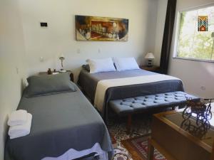 a bedroom with two beds and a bench and a window at Chales Vinhas da Harmonia l Pousada em Cunha SP in Cunha
