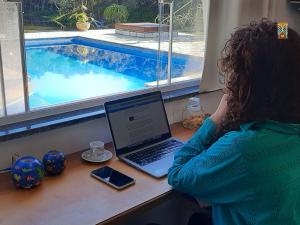 a woman sitting at a desk with a laptop next to a swimming pool at Chales Vinhas da Harmonia l Pousada em Cunha SP in Cunha +27 photos