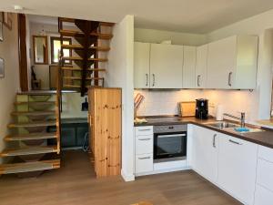 eine Küche mit weißen Schränken und einer Wendeltreppe in der Unterkunft Ferienhäuser am Vogelpark - Boddenhaus 60 in Marlow