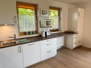 eine Küche mit weißen Schränken und einer Mikrowelle in der Unterkunft Ferienhäuser am Vogelpark - Boddenhaus 60 in Marlow + 20 Fotos