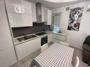 a kitchen with white cabinets and a table and a sink at Appartamento Lindo e Dora - A due passi dal mare in San Benedetto del Tronto