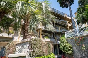 eine Palme vor einem Gebäude in der Unterkunft GuestHost - Modern Escape with Pool & Sunny Terrace in Sanremo