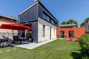 a house with a patio with a table and an umbrella at La villa d'Alix avec jardin et parking in Bègles