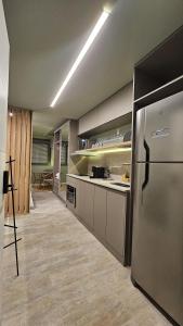 a kitchen with a stainless steel refrigerator and cabinets at Estúdio Moderno em área nobre de Porto Alegre - Conforto e Aconchego em Cada Detalhe in Auxiliadora