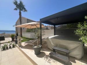 a patio with a bed and an umbrella at Two Palms in Duće