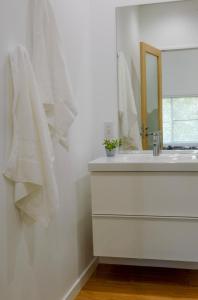 a white bathroom with a sink and a mirror at Cortina Apartment in Otari +8 photos