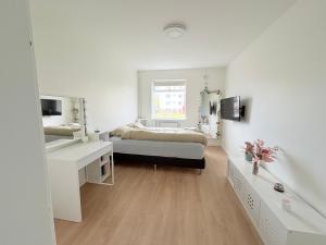 una camera da letto bianca con un letto e una scrivania di Midnight Sun Apartment a Reykjavik