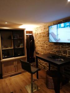 a living room with a television on a brick wall at Charmante maison de vacances 45 minutes des plages in Bains-sur-Oust