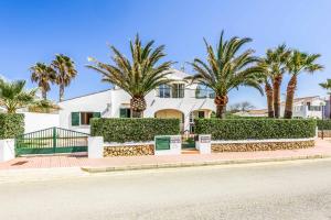 a white house with palm trees in front of it at Villa Sofia in Cala en Forcat