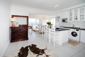 cocina con electrodomésticos blancos y comedor en Luxury Seaside Apartment, en St Francis Bay