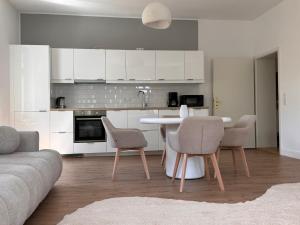 a kitchen with white cabinets and a table and chairs at Apartment 2 am Werlsee in Grünheide