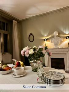 una mesa con platos y un jarrón de flores. en Les Villas du Parc, en Vittel