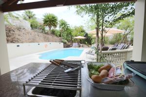 格罗斯岛Cap Pavilion, St Lucia 6 bed luxury villa, private pool, gardens and 360' sea views的游泳池旁的烧烤食品
