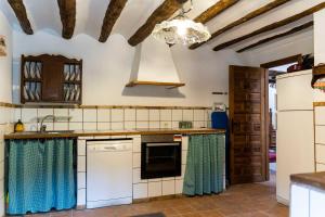 a kitchen with white appliances and blue curtains at Alojamiento Rural ERMITA SAN JULIAN in Burunchel