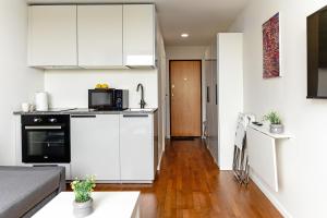 eine Küche und ein Wohnzimmer mit weißen Schränken in der Unterkunft Taikos STUDIO Apartamentai-2 in Klaipėda