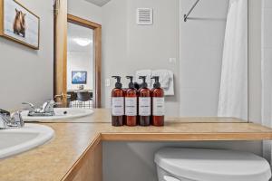 Cuatro botellas de vino sobre un mostrador en un baño. en CHARMING 1 Bdrm plus loft with VIEWS managed by Little Sister Getaways, en Canmore 33 fotos más